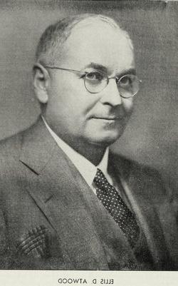 Black and white photograph of a white man with short gray hair and glasses, dressed in a suit and tie. A caption at the bottom reads: “Ellis D. Atwood.”